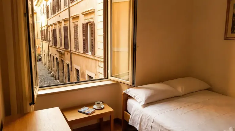 Camera singola economica con finestra aperta che si affaccia su una strada acciottolata di Roma