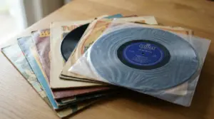 Pile di dischi in vinile con copertine vintage e un 45 giri in busta protettiva su un tavolo di legno