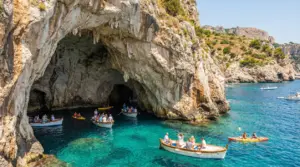 Grotte marine in una scogliera rocciosa con barche e kayak su acqua turchese lungo la costa italiana