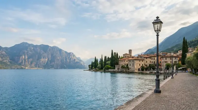 Lungolago del Lago di Garda con borgo storico, lampioni e montagne sullo sfondo in una giornata tranquilla