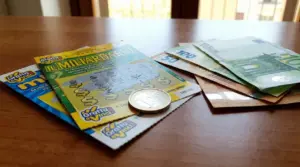 Gratta e vinci e banconote in euro su un tavolo, con una moneta, simbolo di vincita e tasse sul premio